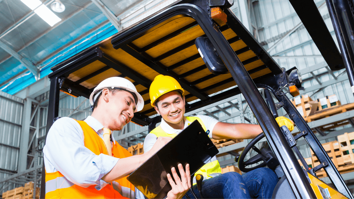 Two builders looking at building plans in a well-lit warehouse