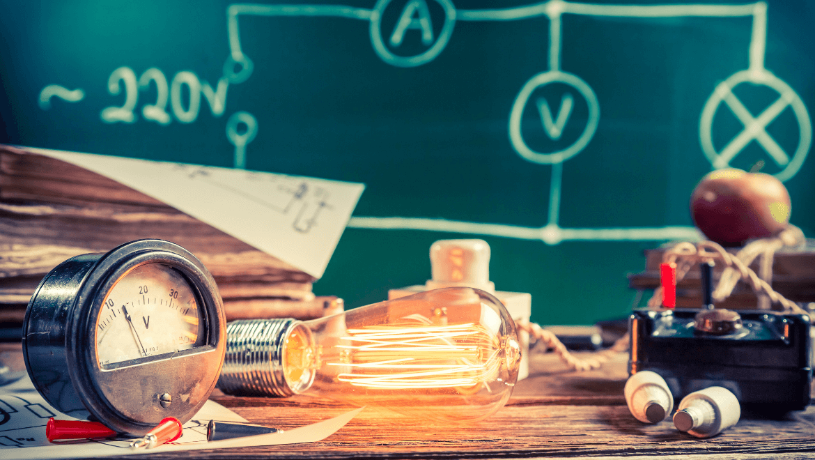 Desk with documents and a lit bulb with a chalkboard in the background