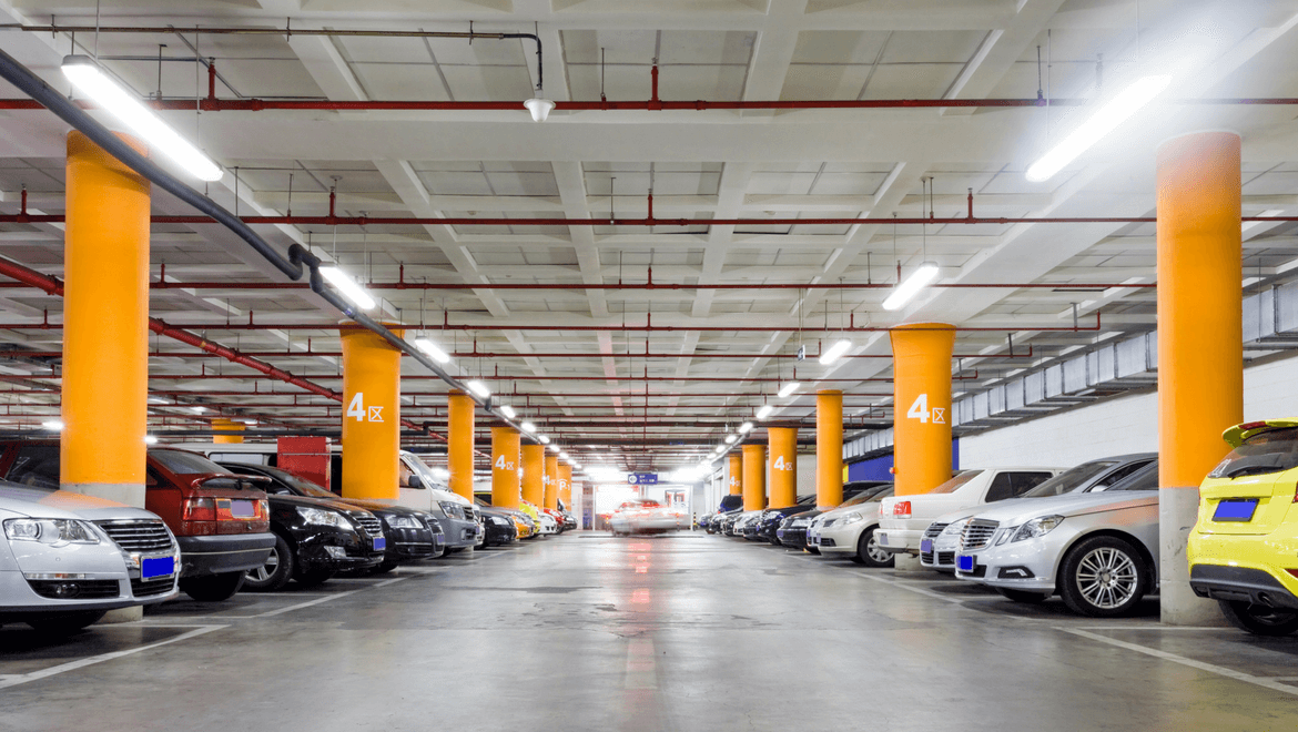 Indoor parking lot lit with cars and orange poles