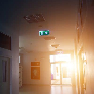 A Running man emergency sign in a deserted hallway shows where we are at in terms of the evolution of emergency lighting in Canada today / L'enseigne de l'homme qui court dans un corridor montre bien l'évolution de l'éclairage d'urgence au Canada